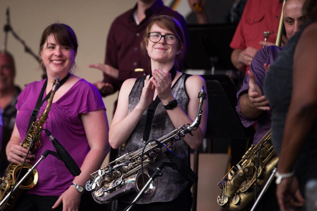 Saxophone players of the Milwaukee Jazz Orchestra smile and clap after they perform a song with Mich